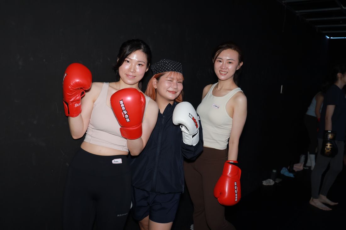 三位女生戴著紅色與白色拳擊手套,靠在一起合照