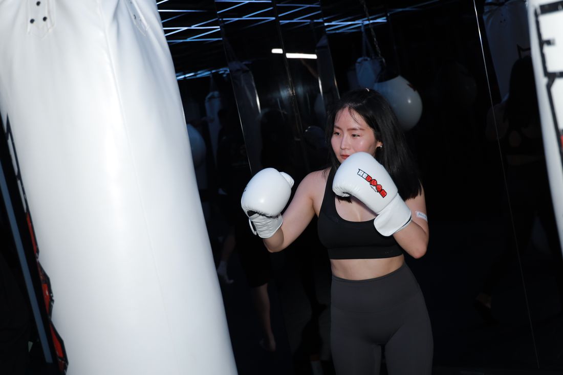 一位女生戴著白色拳擊手套,站在沙包前擺出防守姿勢