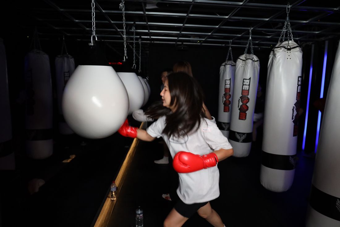 一位穿白色上衣的女生戴紅色手套向沙包出拳,動作帶著殘影