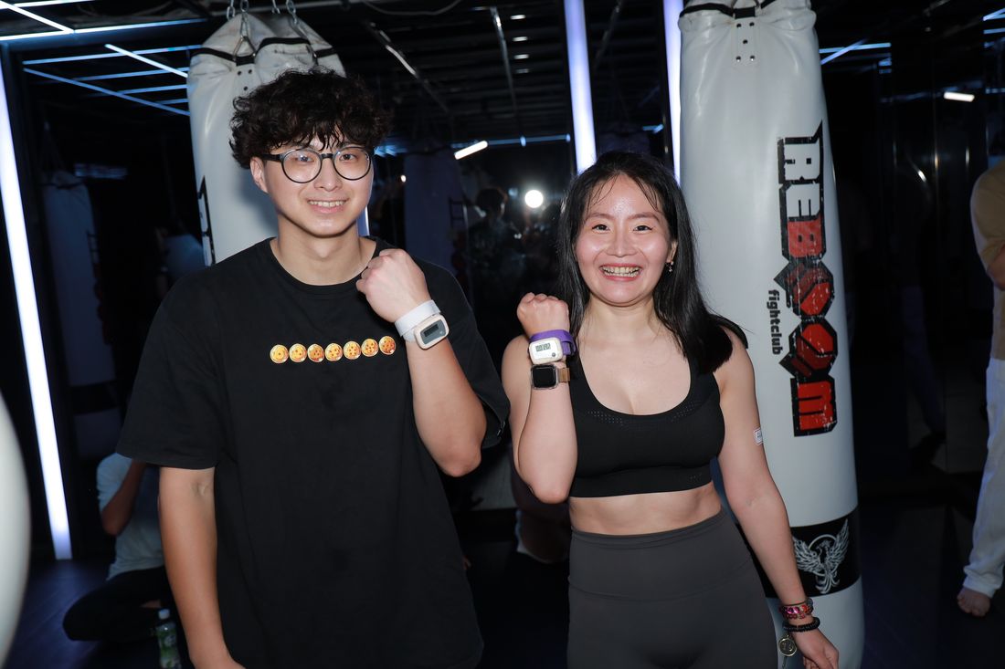 一男一女並肩比出加油手勢,手腕上戴著出拳計數器